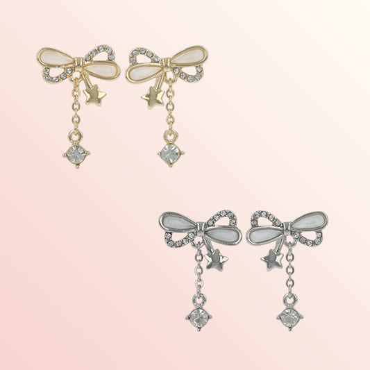 Pair of bow-shaped earrings with star and gemstone details on a light pink background