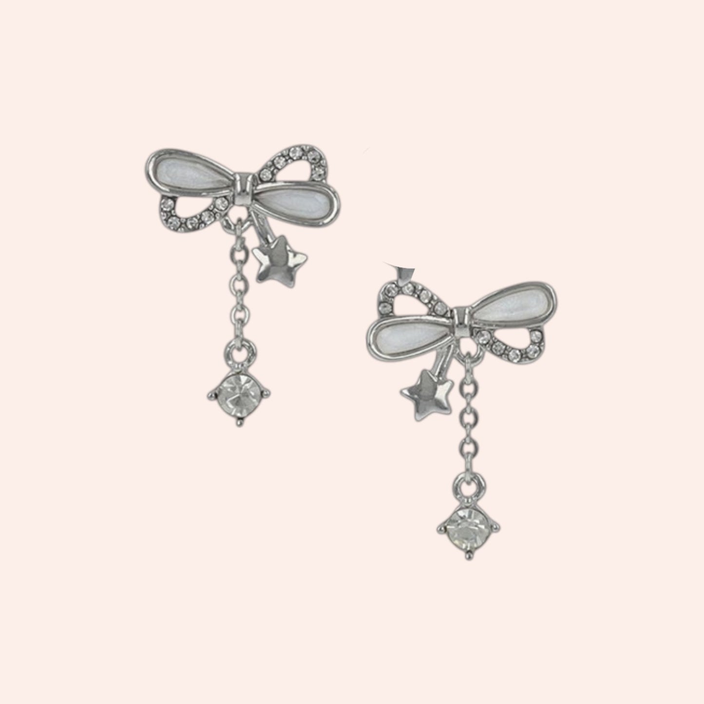 Pair of silver bow-shaped earrings with star and gemstone charms on a light pink background