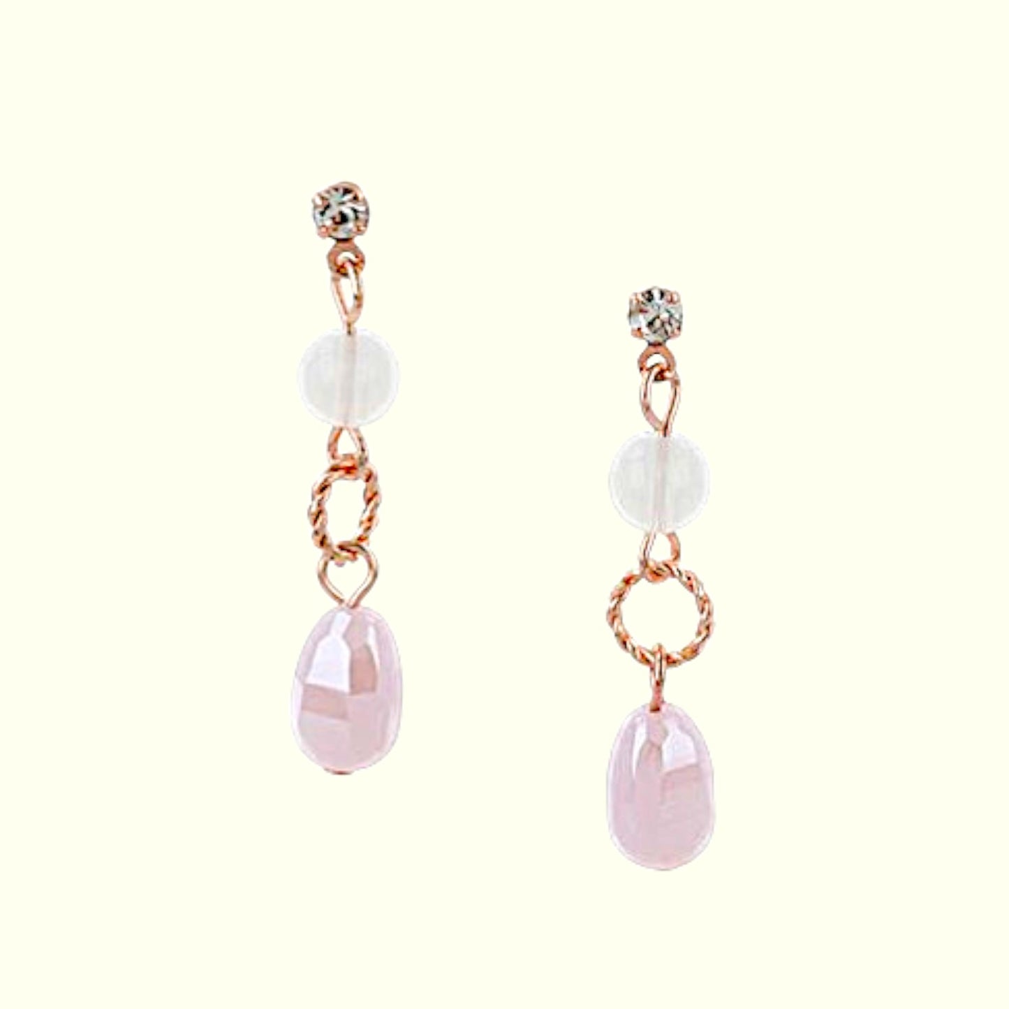 Pair of earrings with pink teardrop-shaped stones and rose gold accents on a white background