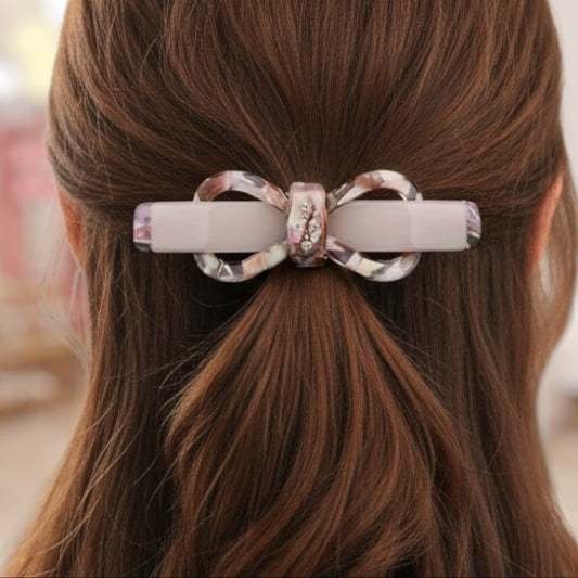 Hair clip with decorative bow on brown hair against a blurred background