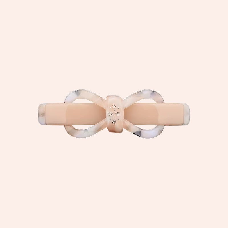 Beige hair clip with a silver bow design on a white background