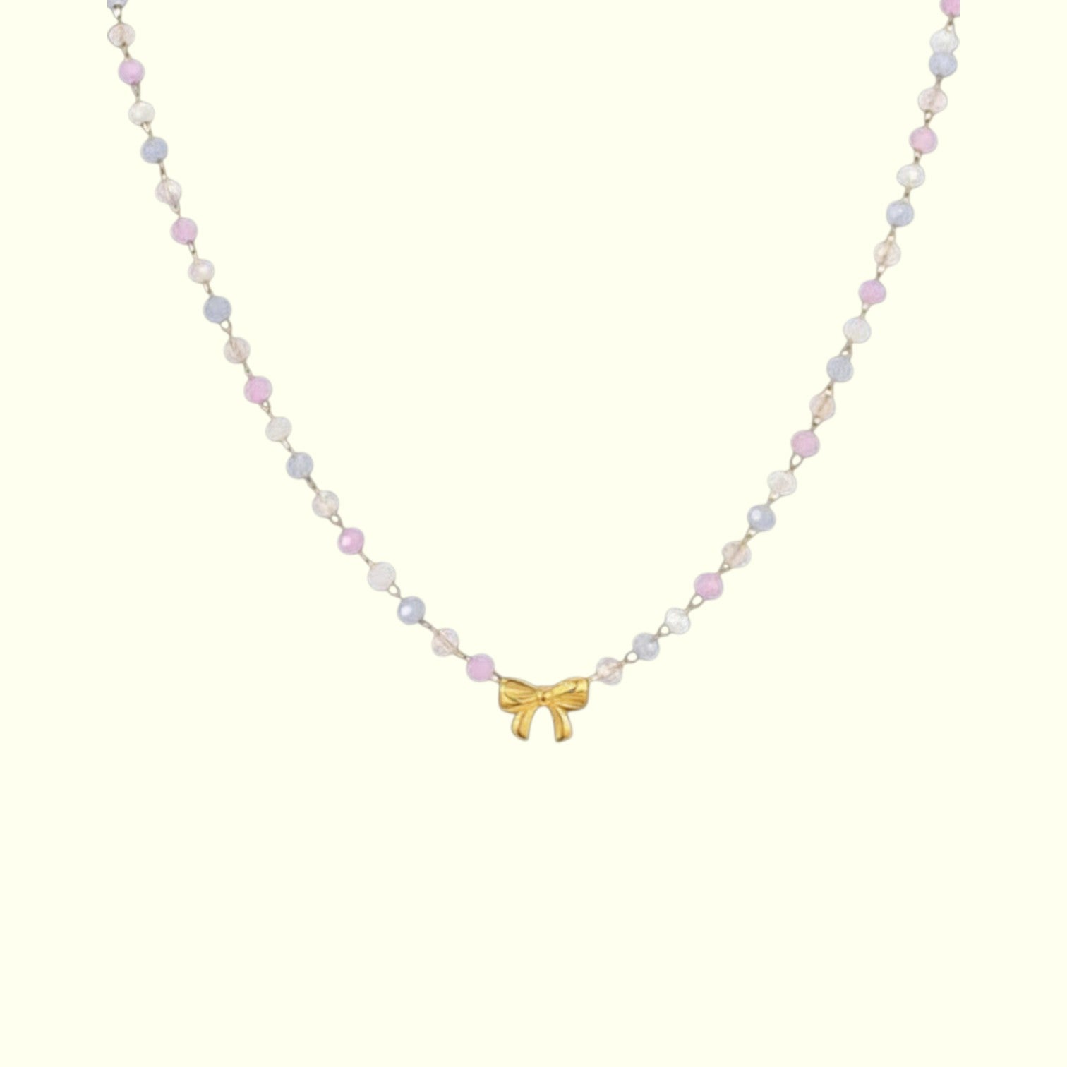 Necklace with pastel bead chain and gold bow pendant on a white background