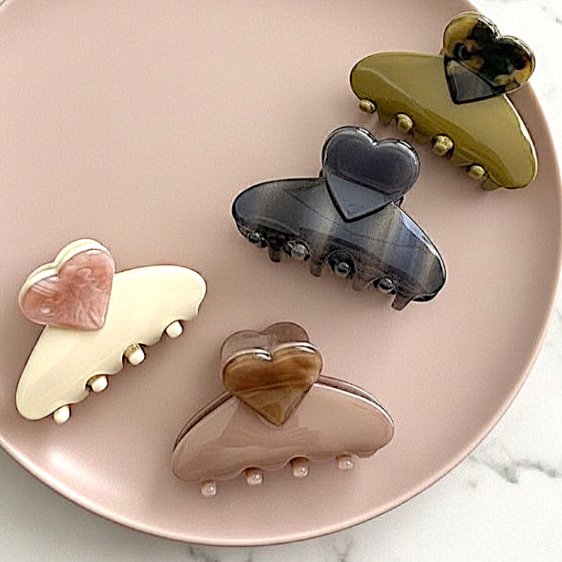Set of heart-shaped hair clips on a pink plate