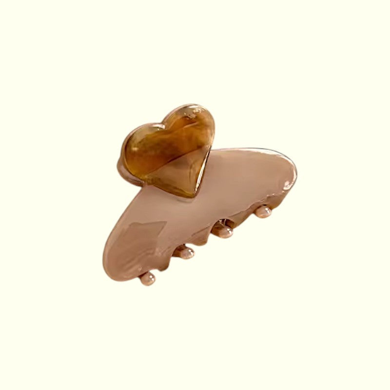 Beige hair clip with a heart-shaped design on a white background