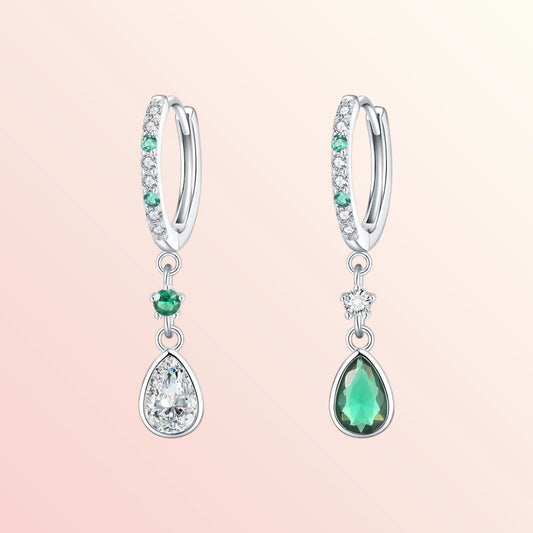 Pair of silver earrings with green gemstones on a light pink background
