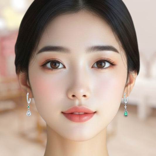 Close-up of a woman wearing emerald green earrings with a blurred background