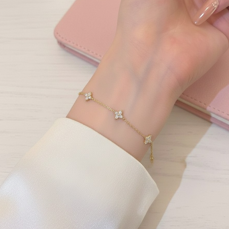 Gold bracelet with floral designs on a wrist against a light background