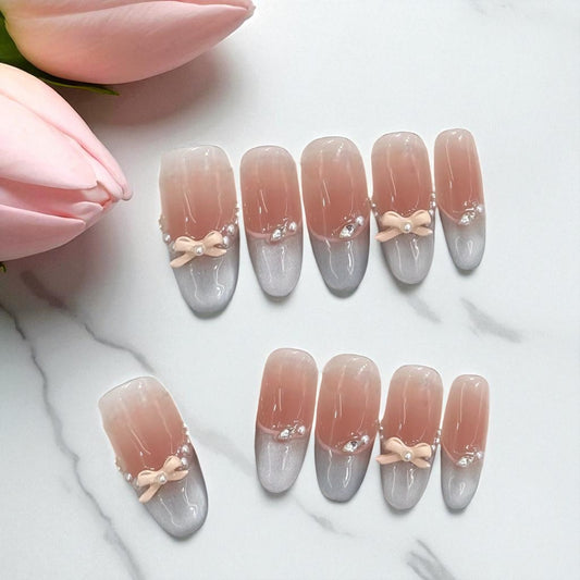 Nail art with gradient design and bow decorations on a white background