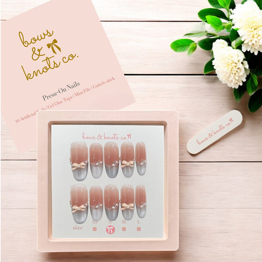 Box of press-on nails with a floral design on a wooden surface, featuring the brand 'bows & knots co'.