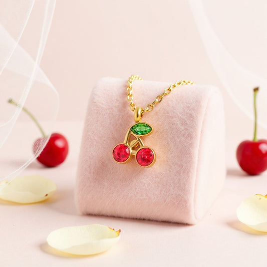 Cherry-themed necklace on a pink cushion with cherry decorations around