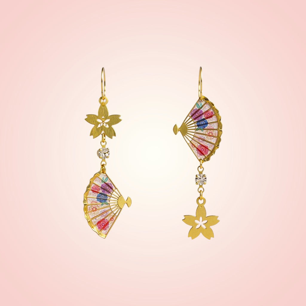 Pair of gold earrings with colorful accents on a pink background