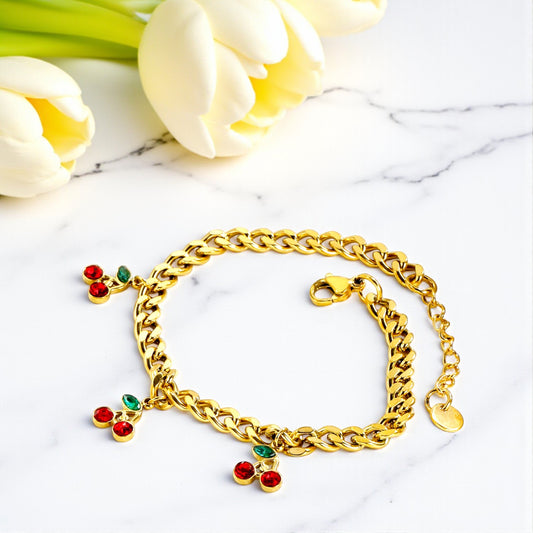 Gold bracelet with colorful charms on a marble surface with tulips in the background