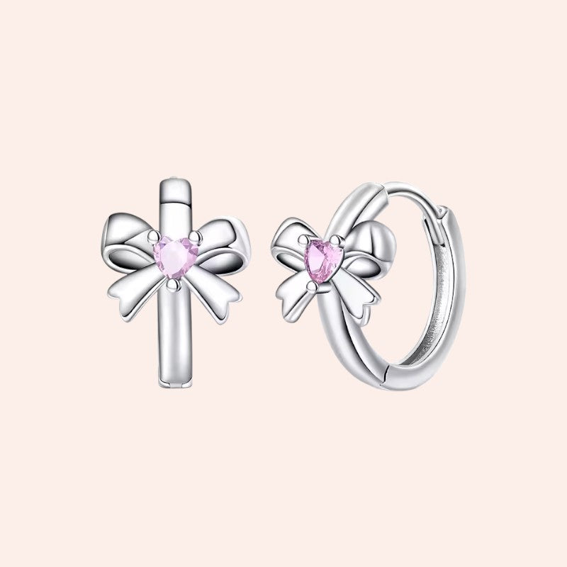 Silver earrings with pink gemstones on a light pink background