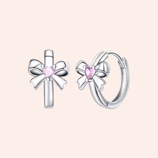 Silver earrings with pink gemstones on a light pink background