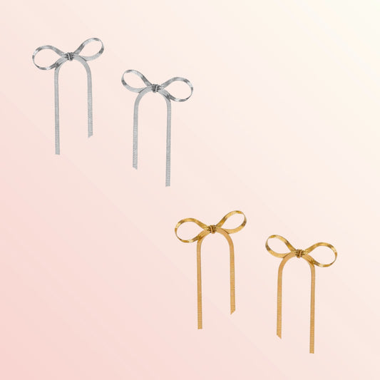 Two pairs of bow-shaped earrings, one silver and one gold, on a light pink background.