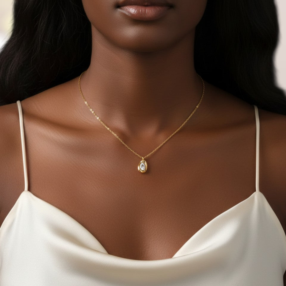 Woman wearing a gold necklace with a green gemstone pendant