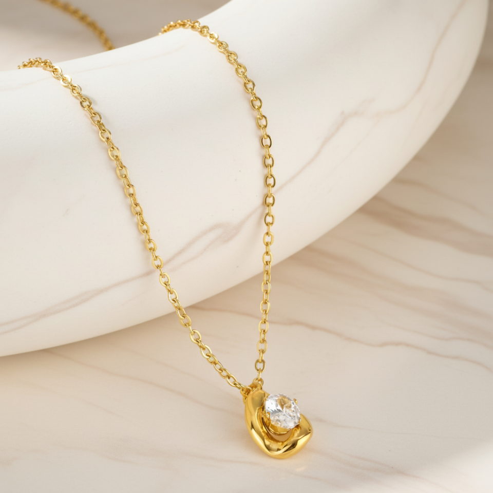 Gold necklace with a diamond pendant on a light background