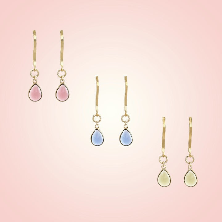 Set of teardrop-shaped earrings on a pink gradient background