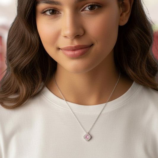 Woman wearing a necklace with a pink pendant against a blurred background