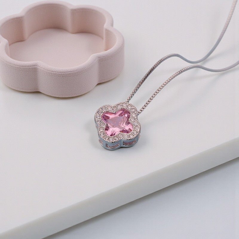 Necklace with a pink clover pendant on a white surface