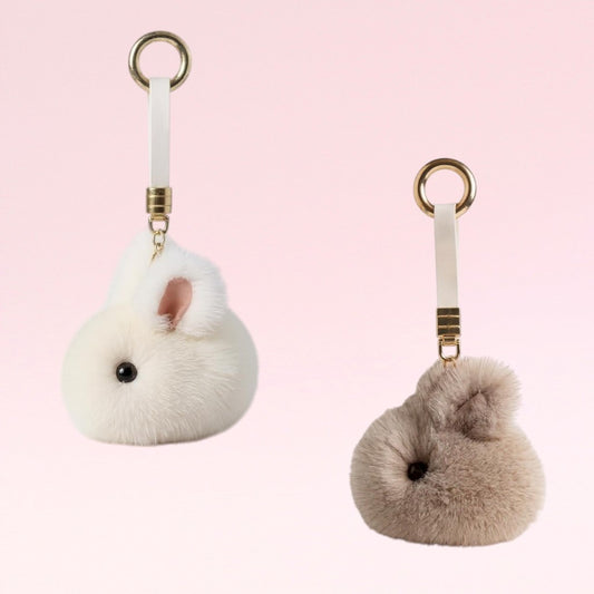 Two fluffy keychains shaped like small animals on a pink background