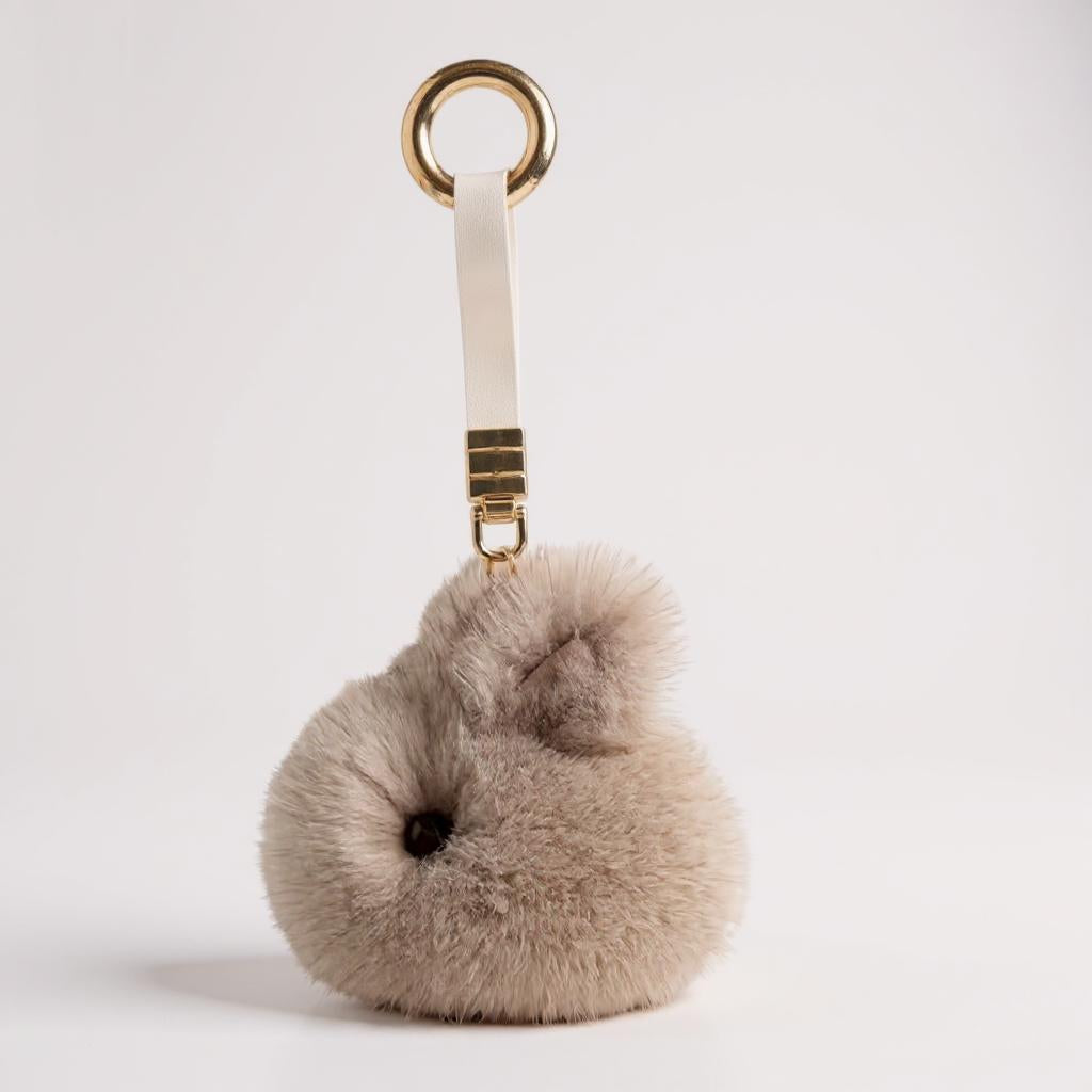Fluffy keychain with a gold ring on a light gray background