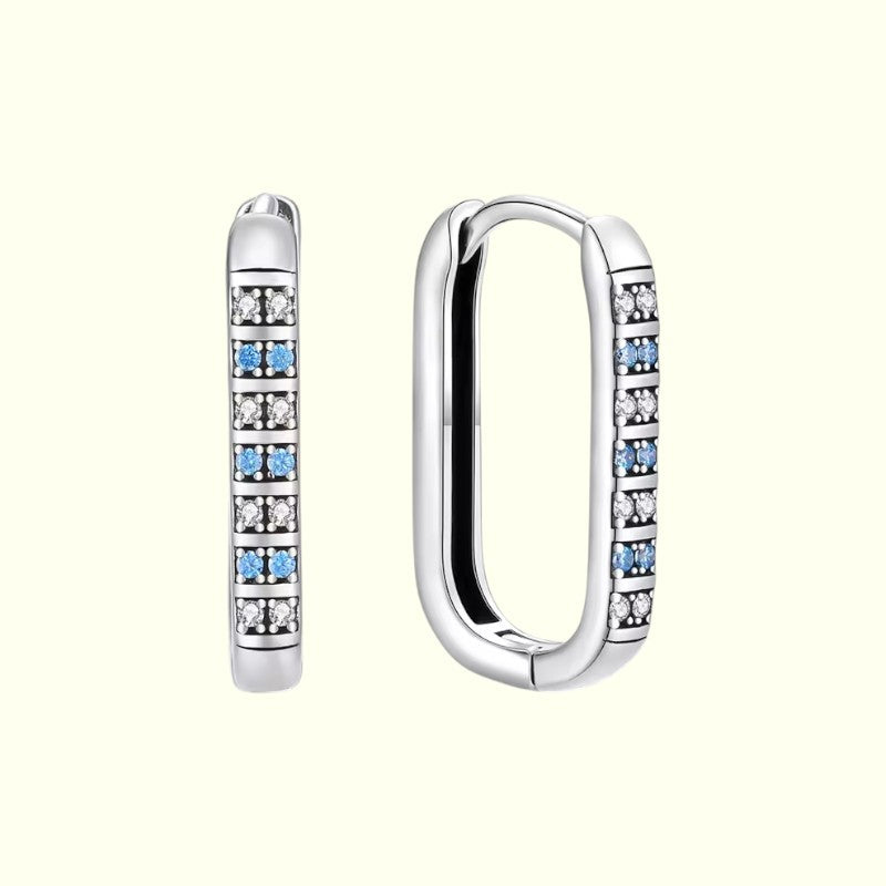 Silver hoop earrings with embedded blue and clear gemstones on a white background