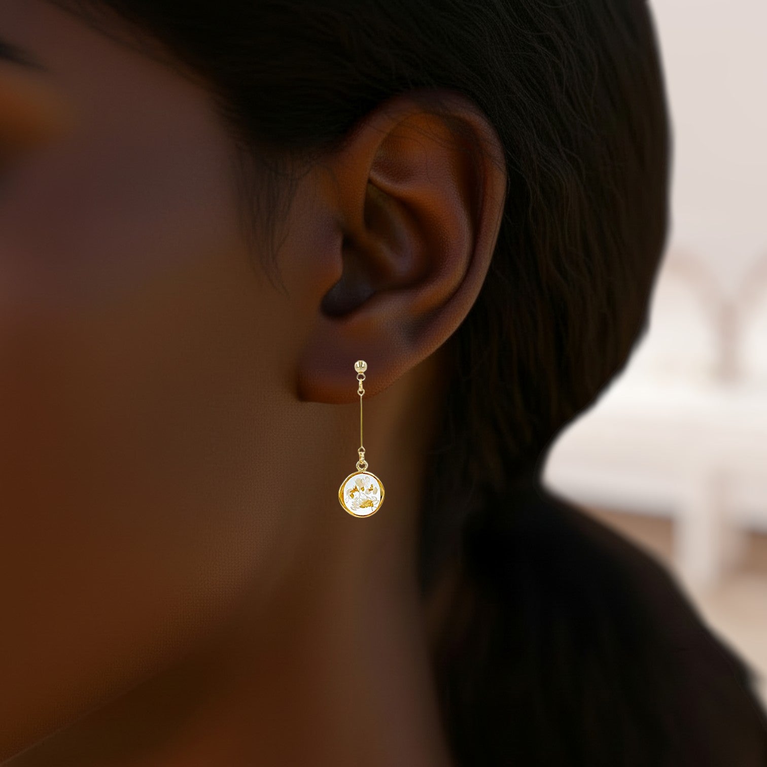Gold earring worn by a person with a blurred background