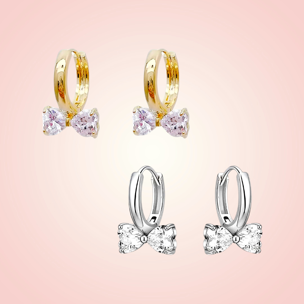 Pair of gold hoop earrings with pink gemstones on a pink background