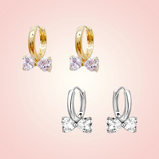 Pair of gold hoop earrings with pink gemstones on a pink background