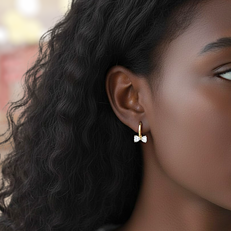 Close-up of a person wearing a bow-shaped earring with a blurred background