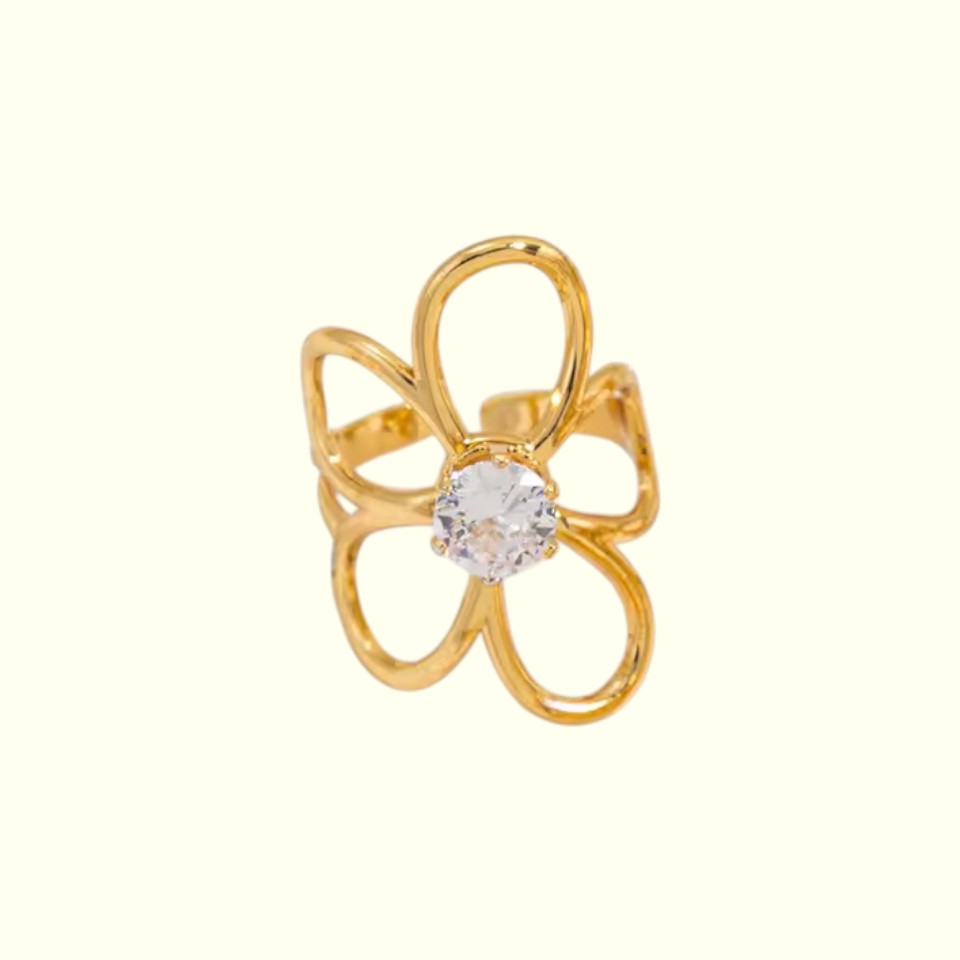 Gold flower-shaped ring with a central gemstone on a white background