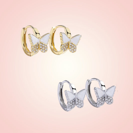 Butterfly-shaped hoop earrings in gold and silver on a pink background