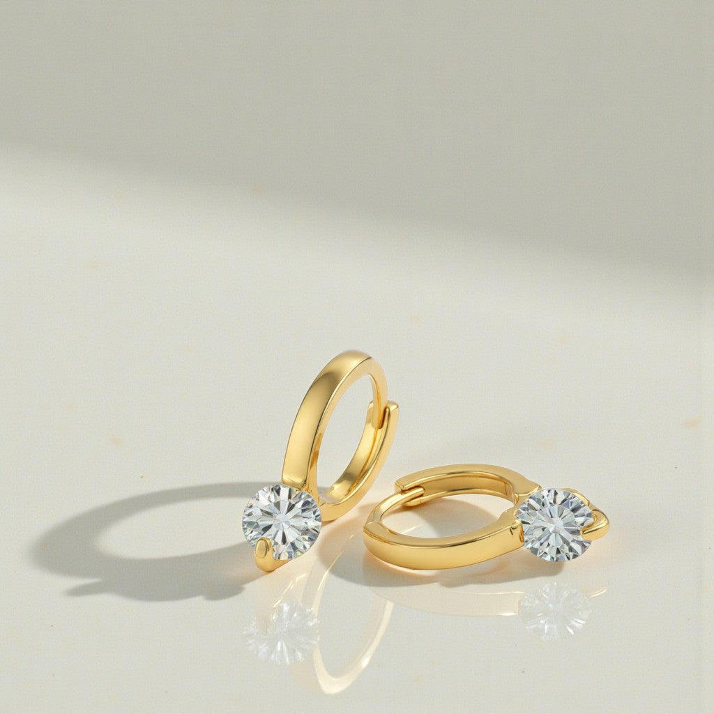 Gold hoop earrings with clear gemstones on a light gray background