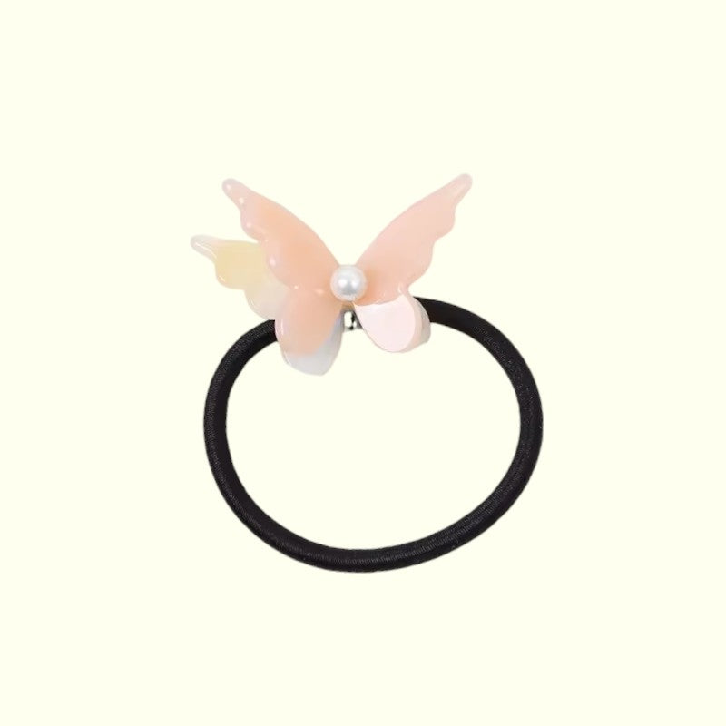 Butterfly-shaped hair tie with a pearl on a white background