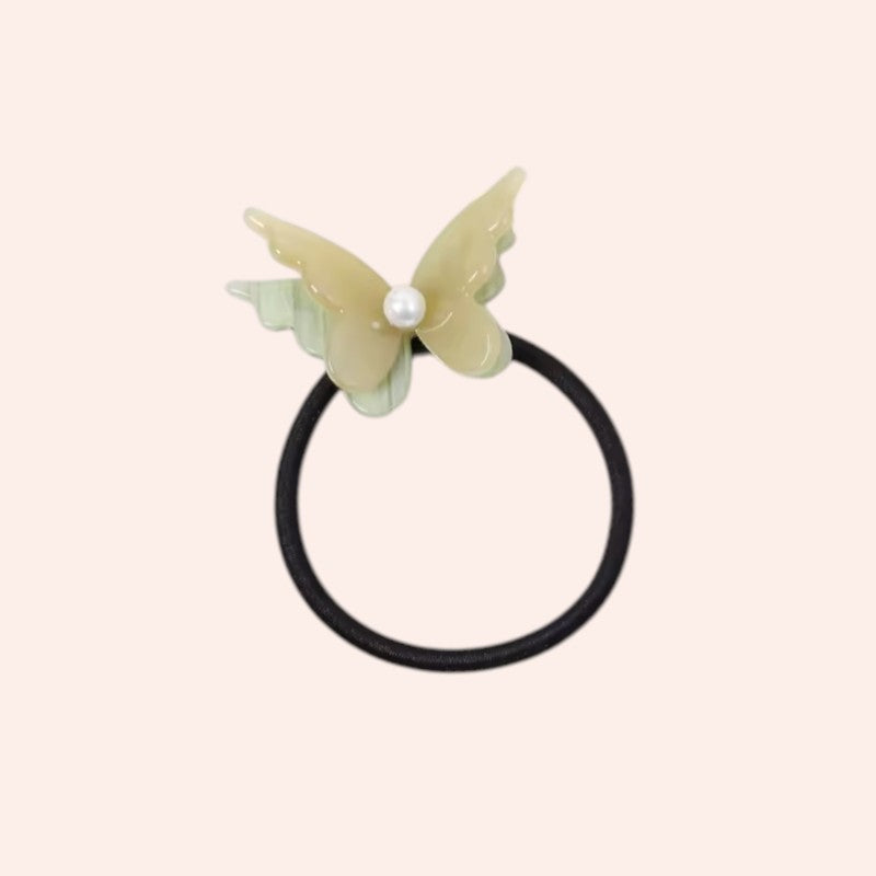 Butterfly-shaped hair tie with a pearl on a light pink background