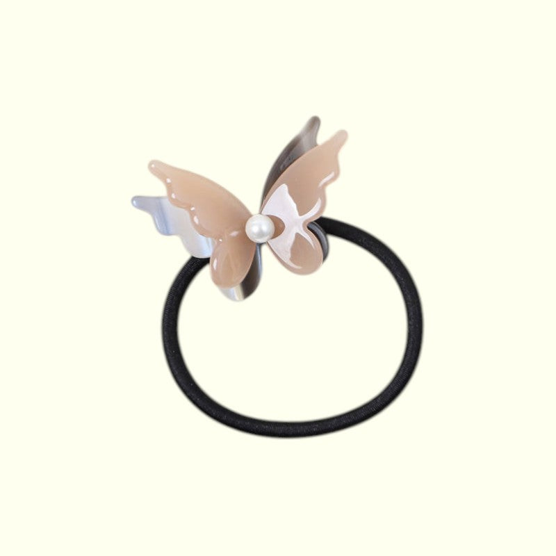 Butterfly-shaped hair tie with a pearl on a white background