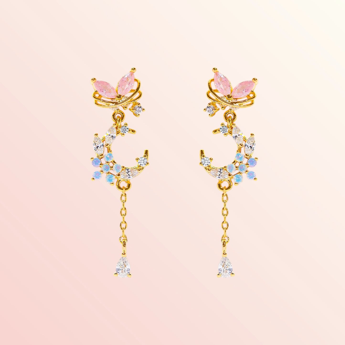 Gold earrings with pink and blue gemstones on a light pink background