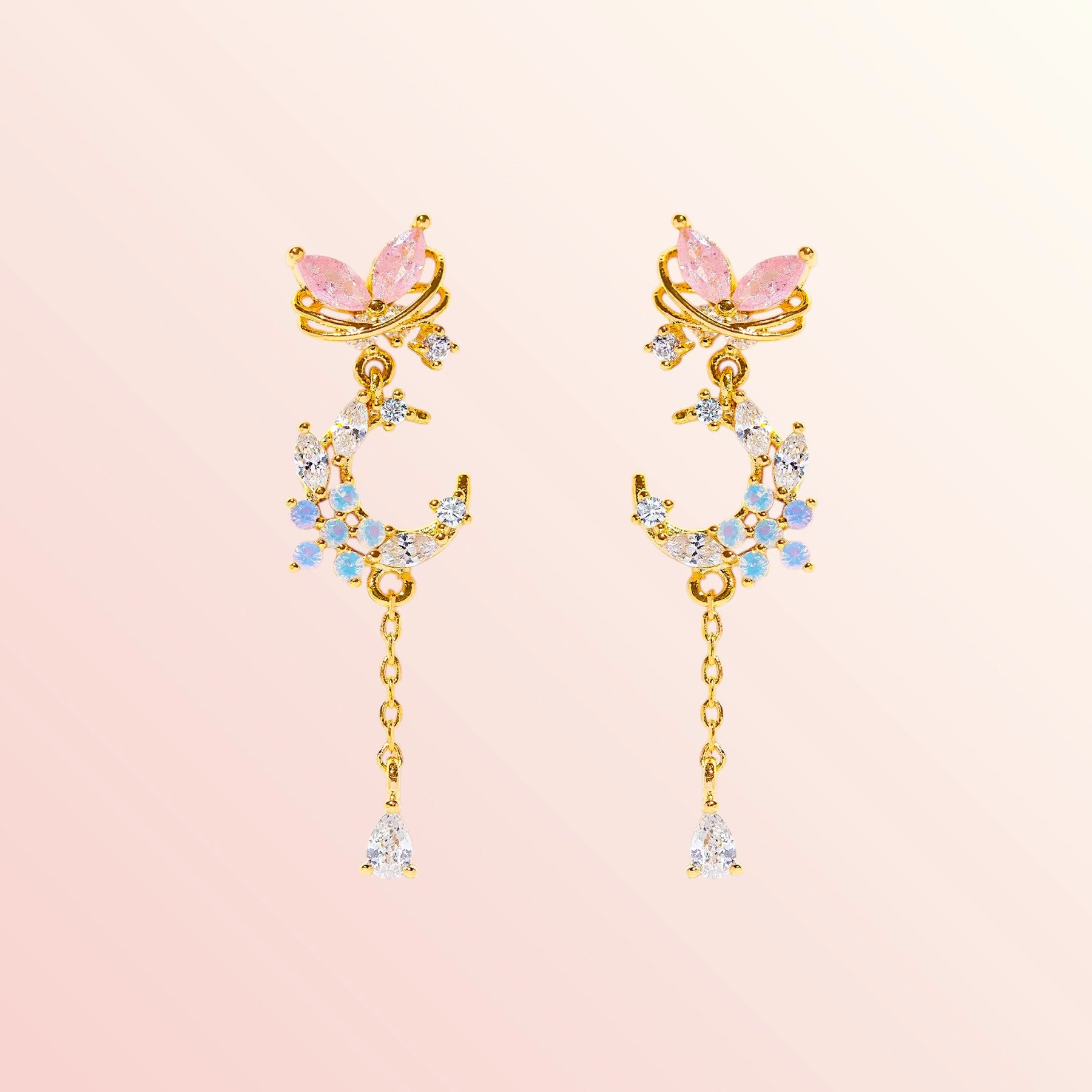 Gold earrings with pink and blue gemstones on a light pink background
