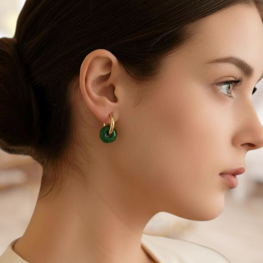Close-up of a woman wearing a gold earring with a green gemstone.