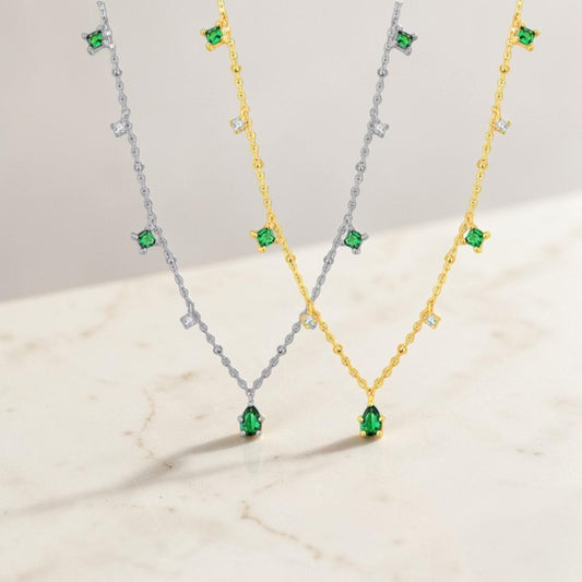 Two necklaces with green gemstones on a light background