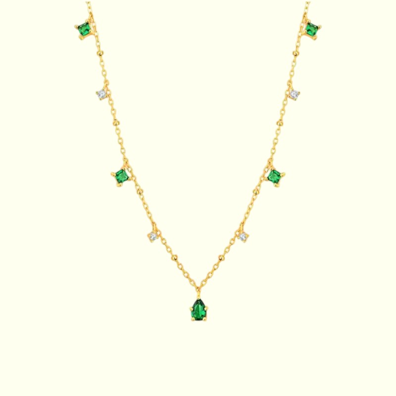 Gold necklace with green gemstones on a white background