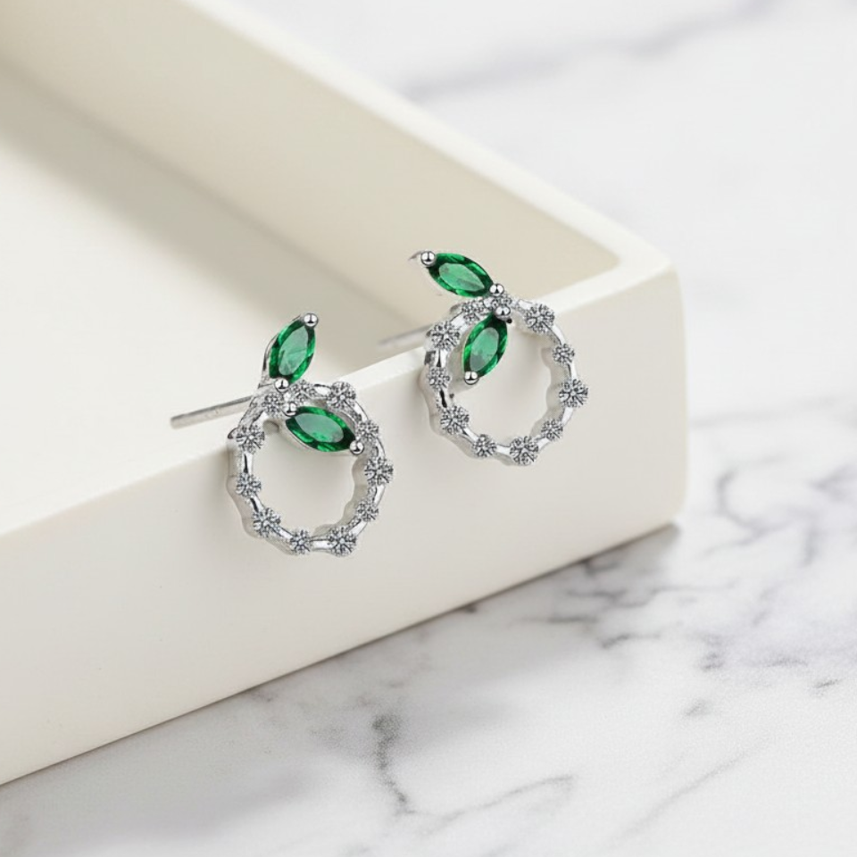 Pair of earrings with green gemstones on a marble surface
