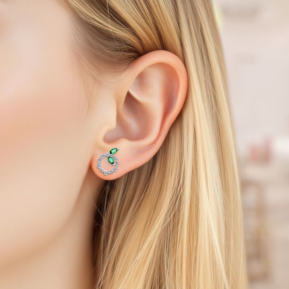 Close-up of an ear wearing a green gemstone earring with blurred background