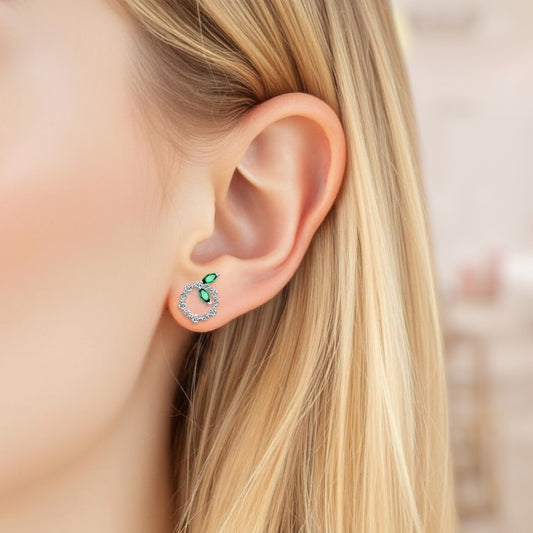 Close-up of an ear wearing a green gemstone earring with blurred background