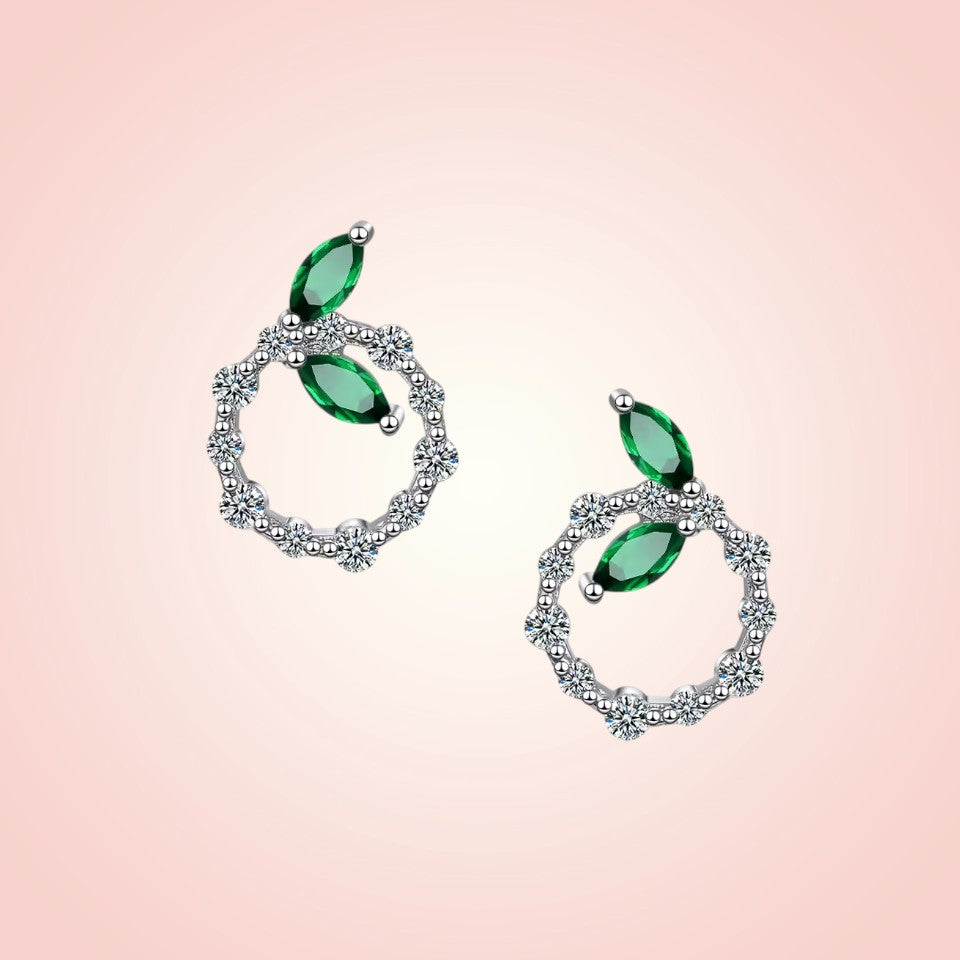 Pair of earrings with green gemstones on a pink background
