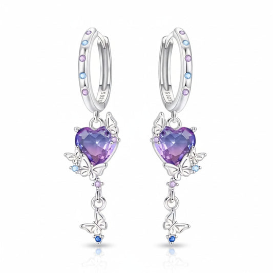 A pair of silver huggie hoop earrings with dangling heart-shaped purple gemstones, butterfly motifs, and small colorful accent stones, shown on a clean white background.