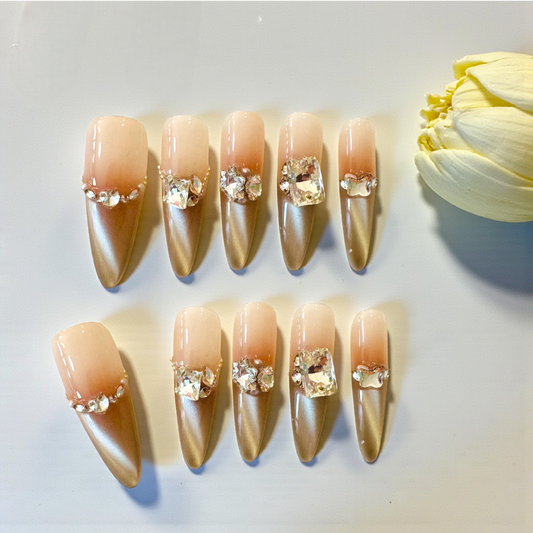 Set of decorative nails with rhinestones next to a white flower on a light background