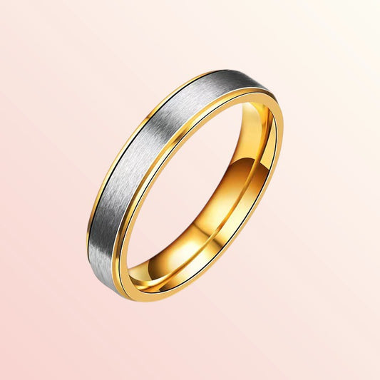 Two-tone gold and silver ring on a light pink background