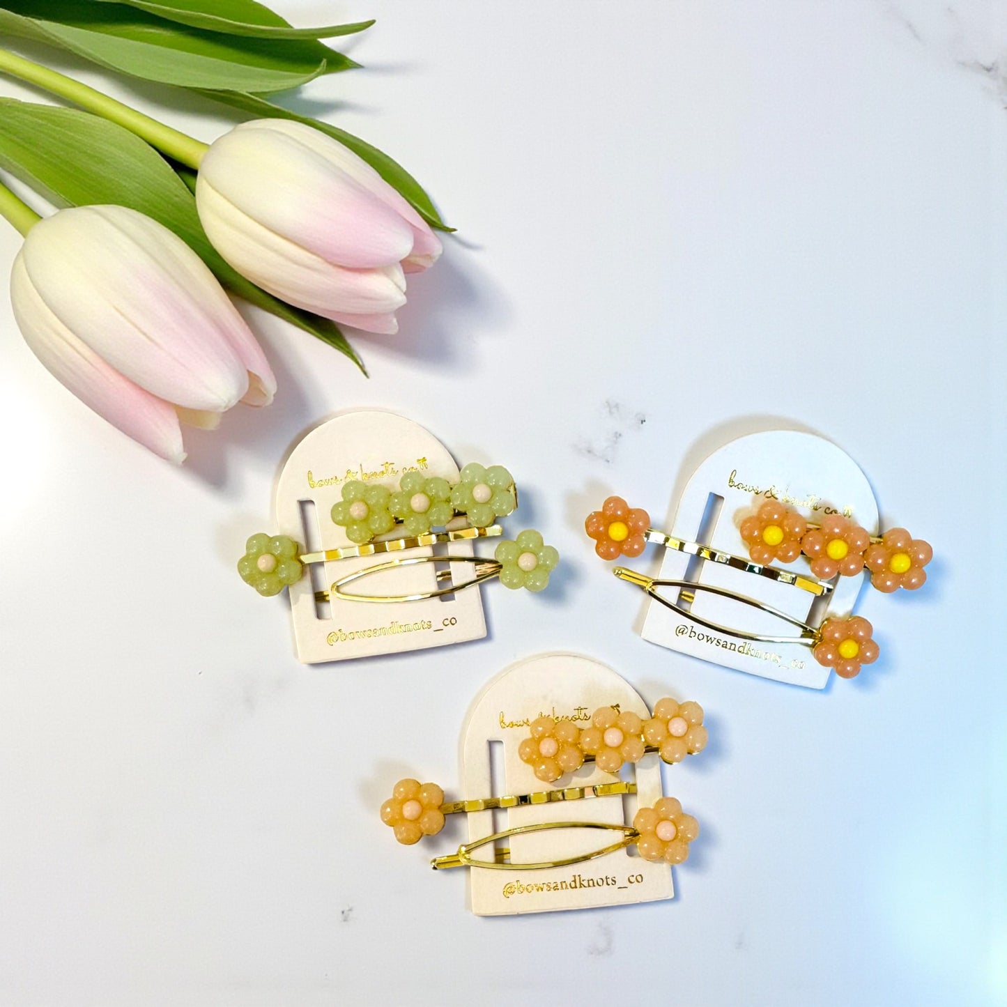 Three floral hair clips on cards with tulips on a light background